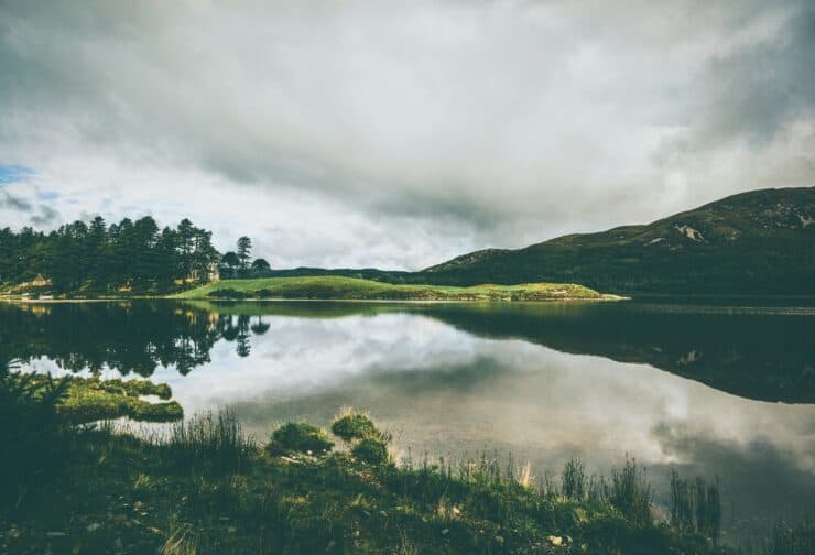 Cloudy day at a lake with rolling green hills; cover image for a blog on the impact of unplanned CEO succession.